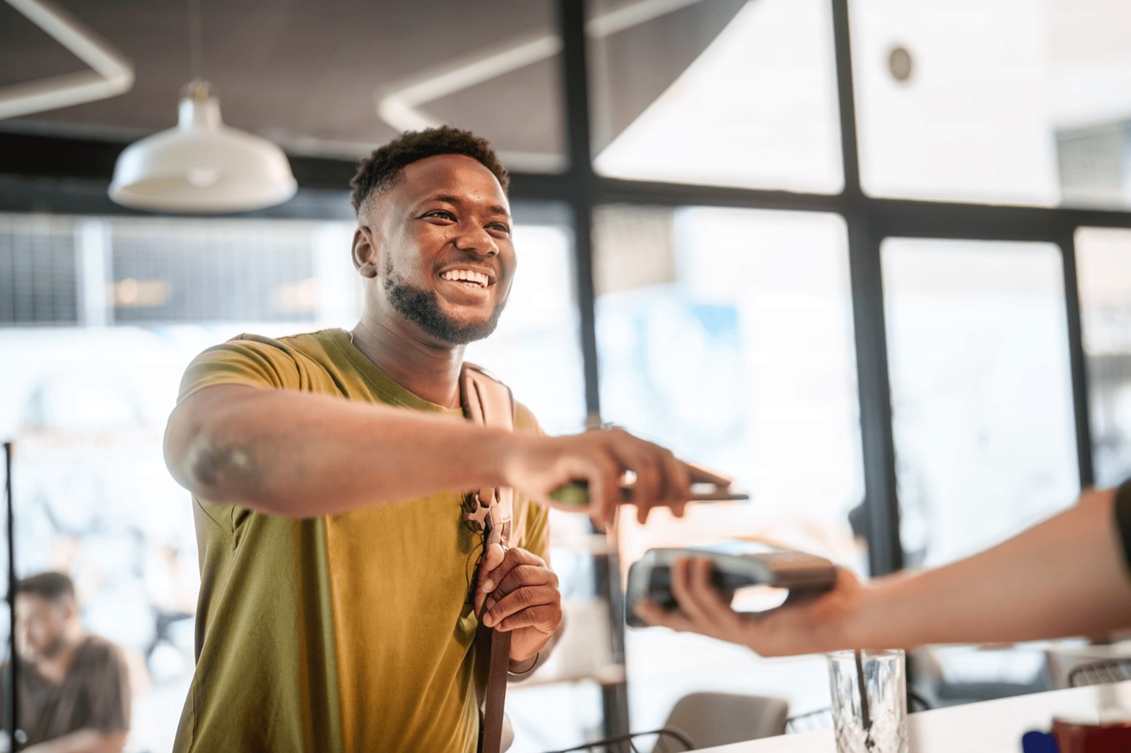 A customer smiling as he taps to pay at a local shop counter